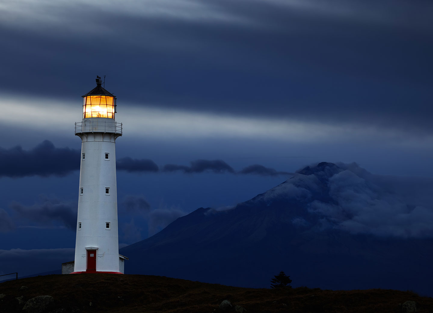 lighthouse in front of mountain