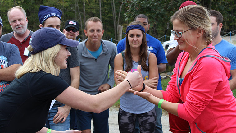 Photo of two women playing a game of rock, paper, scissors in front of their peers