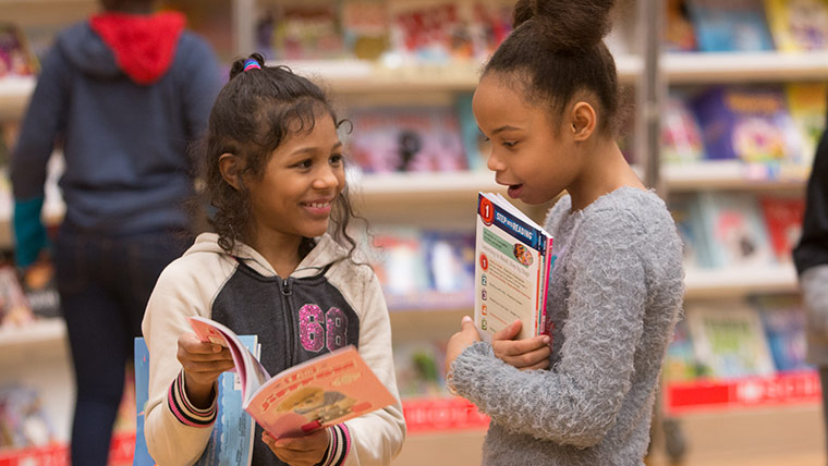 Photo of two young girls looking at books together