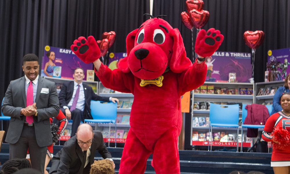 Photo of the Clifford the big red dog mascotwaving to kids in the audience
