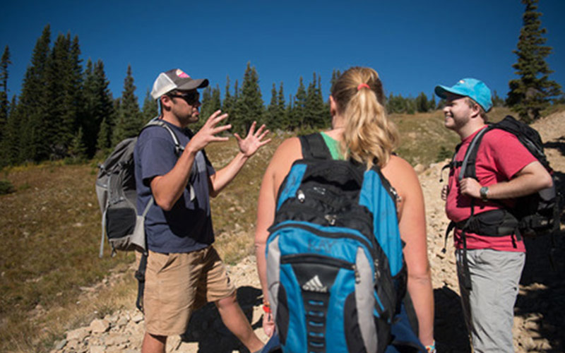 man gestures with hands while speaking to other hikers