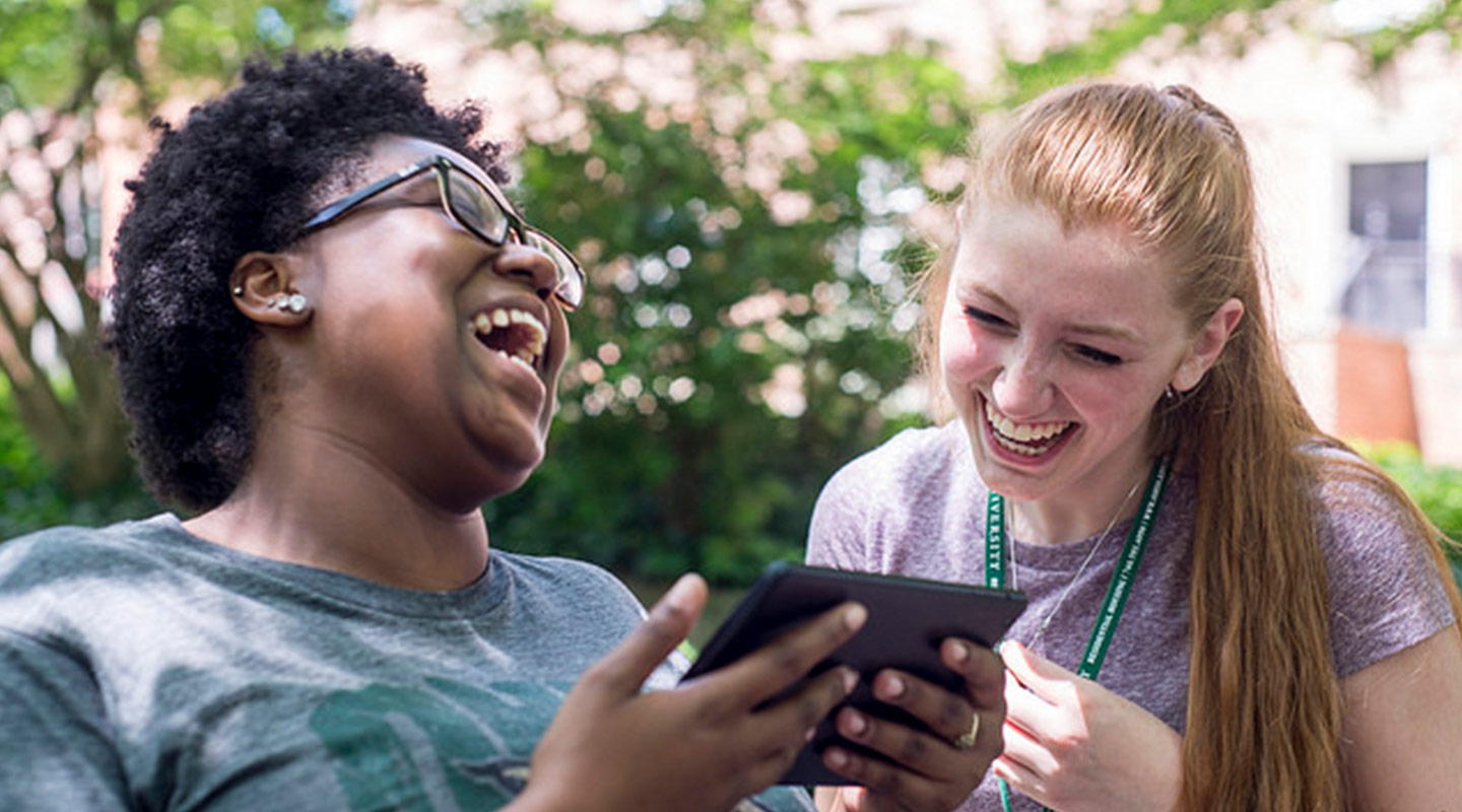 teens laughing while looking at a tablet