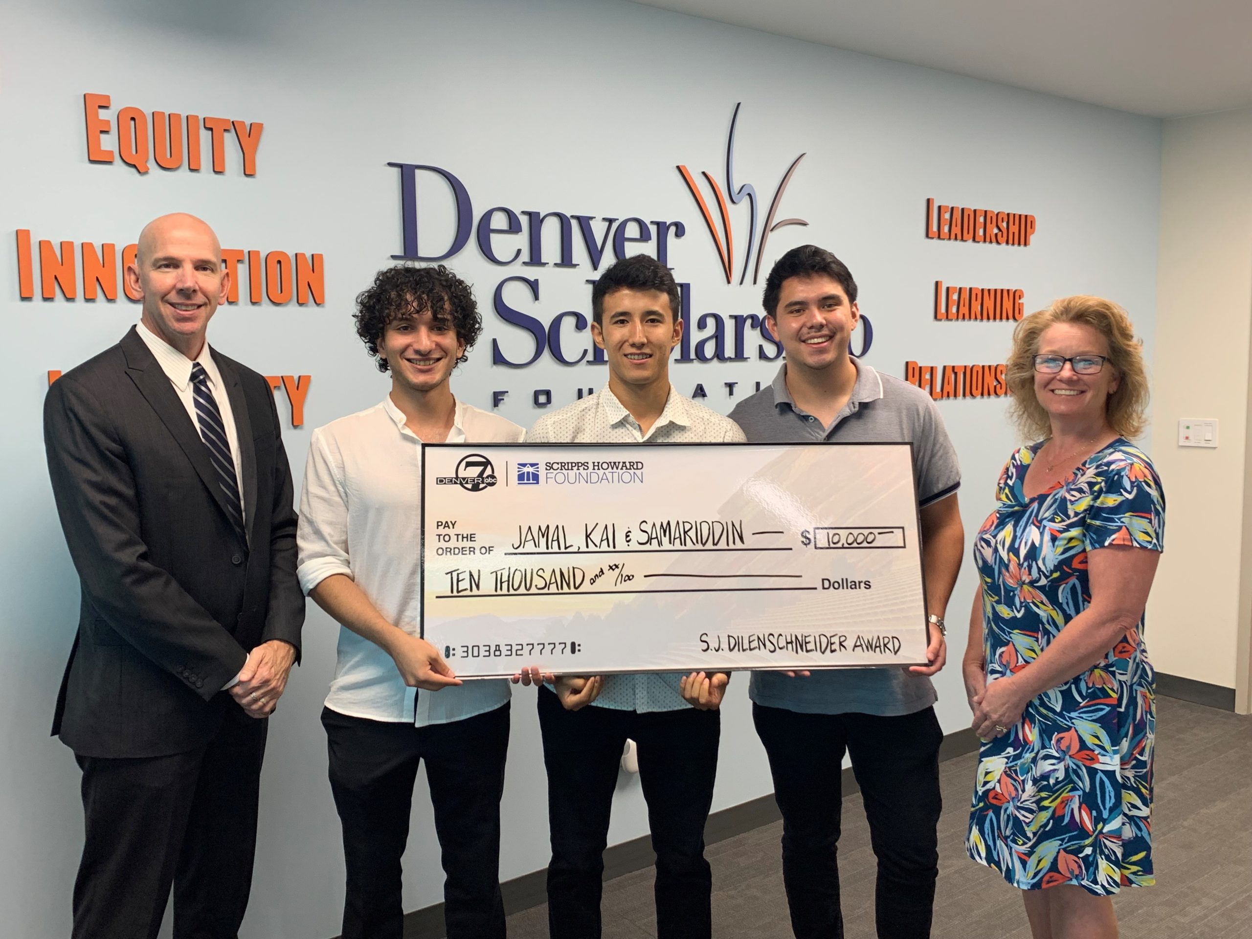 Photo of three men holding a $10,000 check after receiving the S.J. Dilenschneider Community Award with two employees standing beside them
