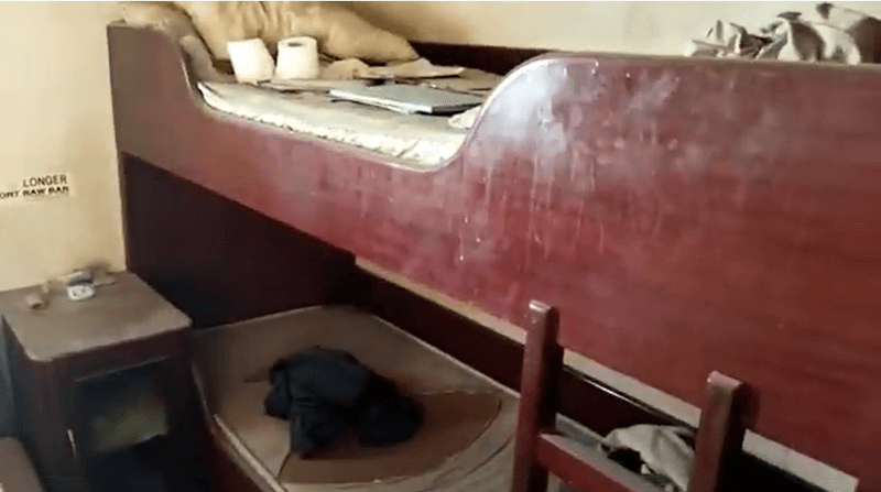 Photo of an old ship bunkbed with dust on it and toilet paper rolls and old papers on the bed