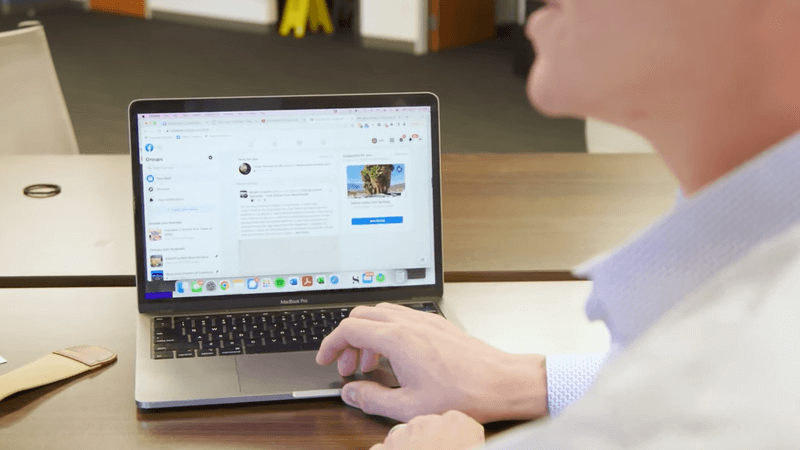 Photo of a man's hand resting on a laptop track pad with a Facebook Events window pulled up on the laptop