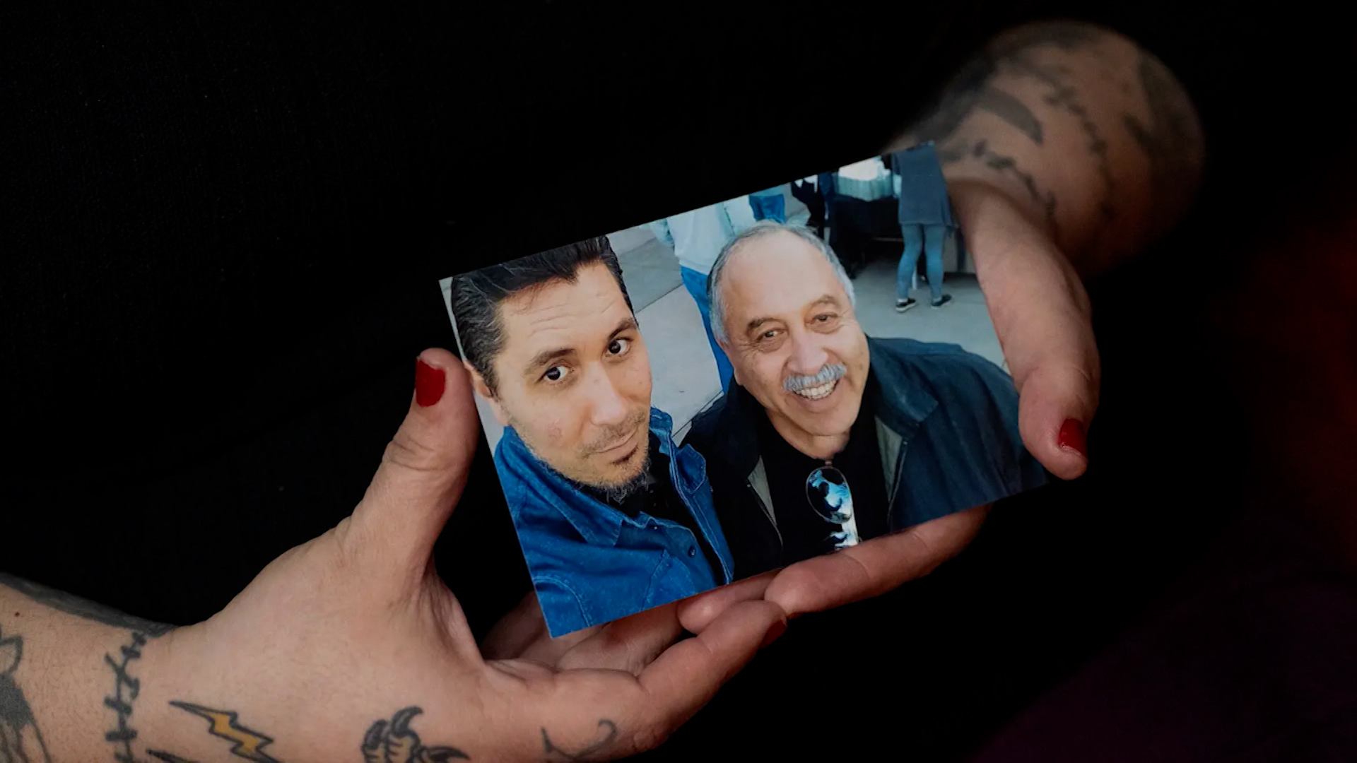 A woman holds a photo of two male family members.