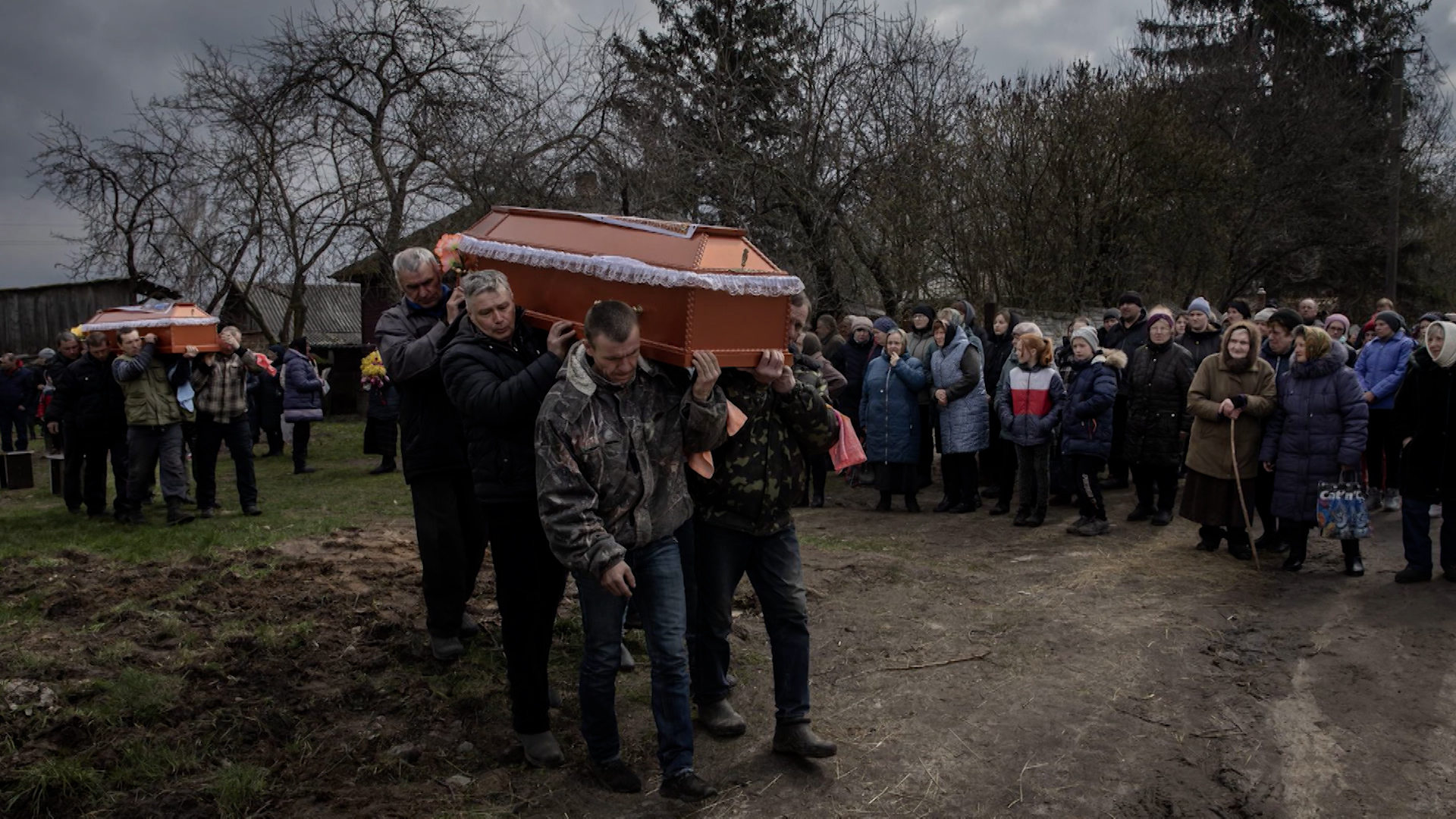 Four pallbearers are carrying a coffin noting the horrors of Russian War Crimes in Ukraine.