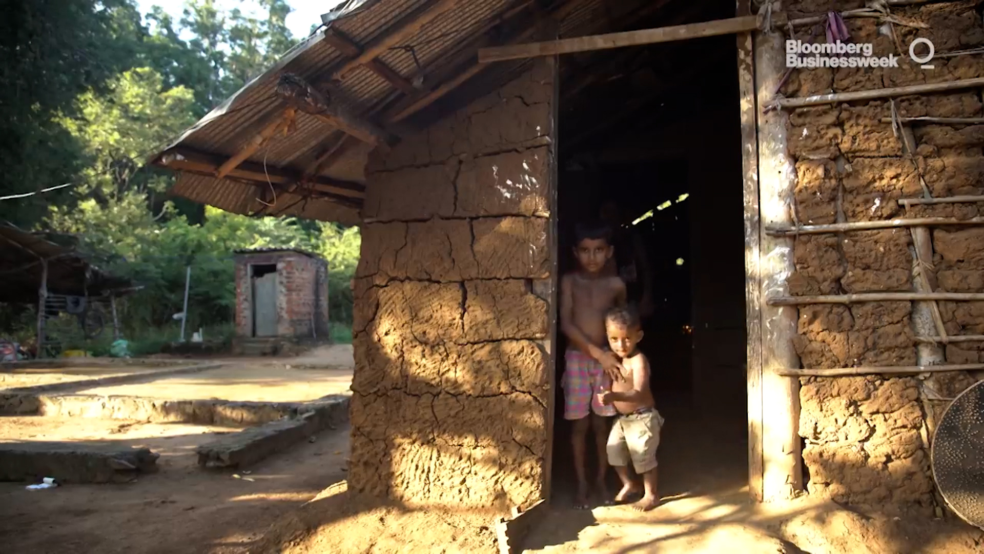 The image is of two young children in a hut. They live in a third world impoverished community.